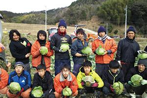 大きなキャベツを持って整列する12人の従業員達の写真