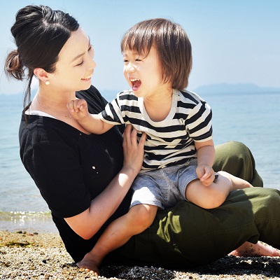 子どもを膝に乗せている、笑顔の女性の写真