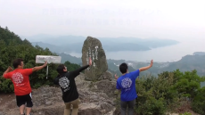 山の石碑のまえに立つ3人の男性の写真