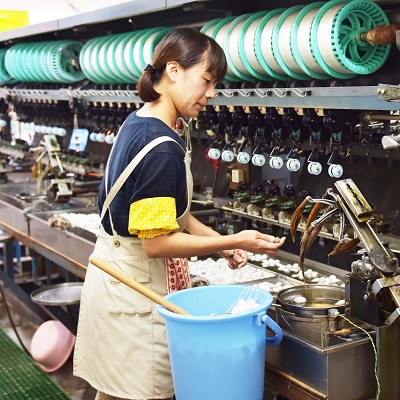 大きな機械で作業をする、エプロン姿の女性